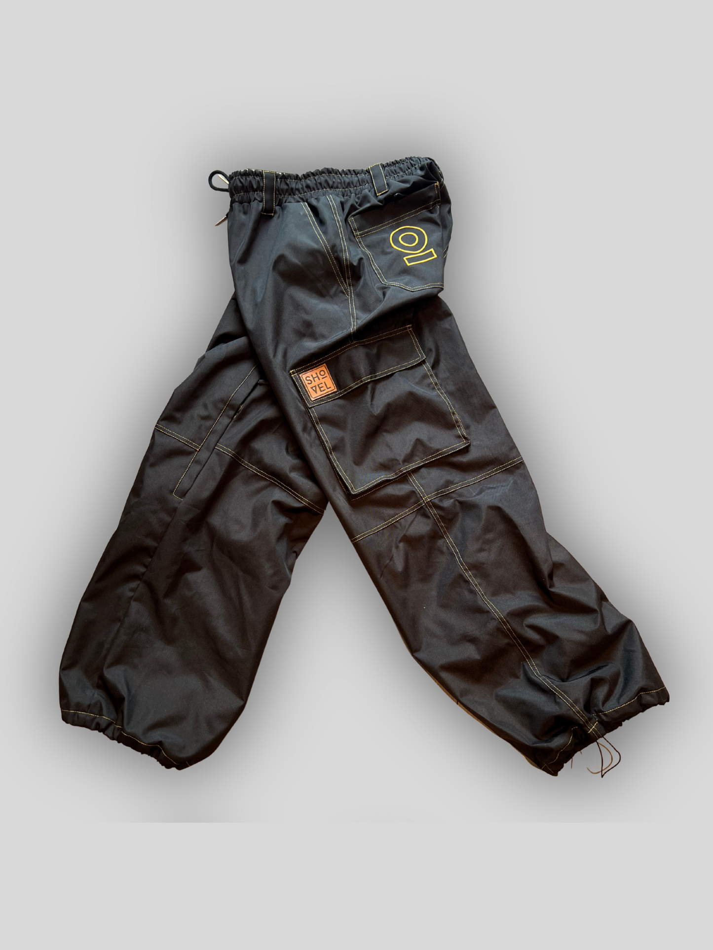 Side view of Black Jean style pants with a brand logo on a light gray background