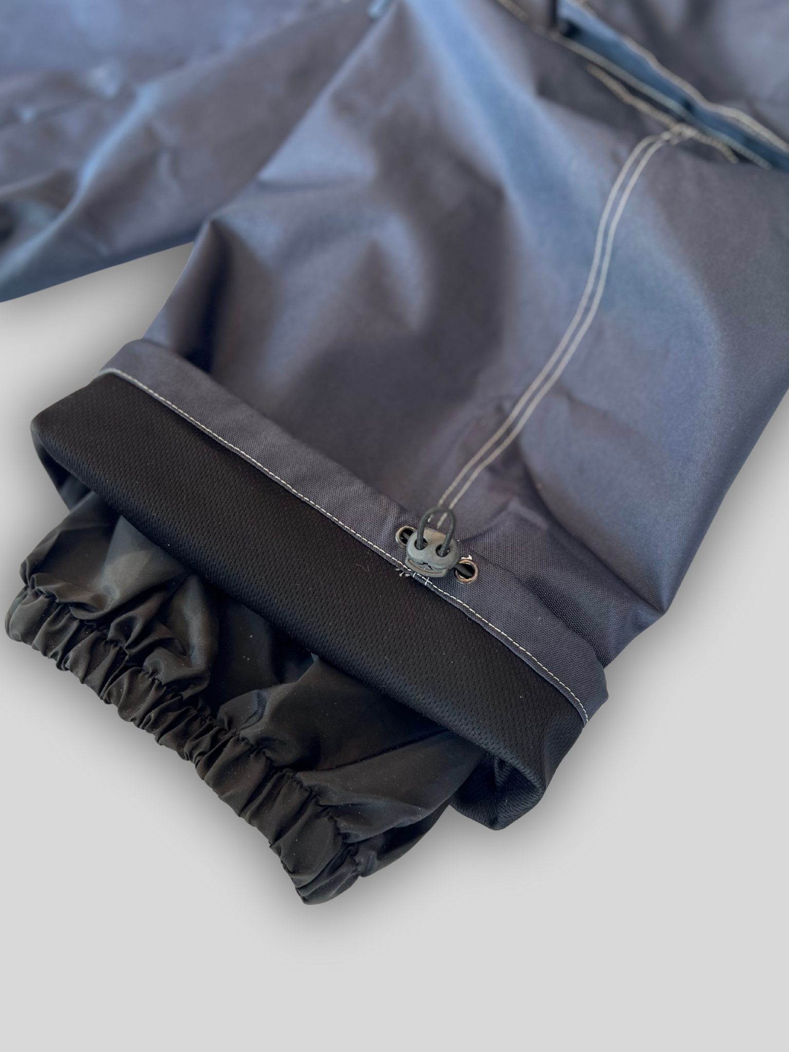 Close-up of a gray raincoat with a zipper on a light gray background